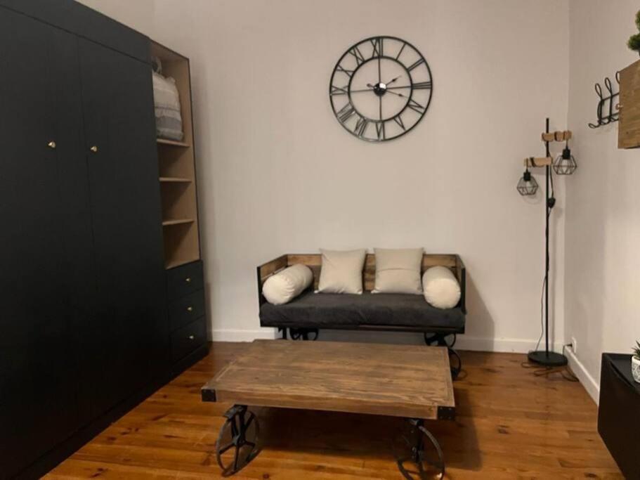 un salon avec un canapé et une horloge au mur dans l'établissement suite totem, à Lyon