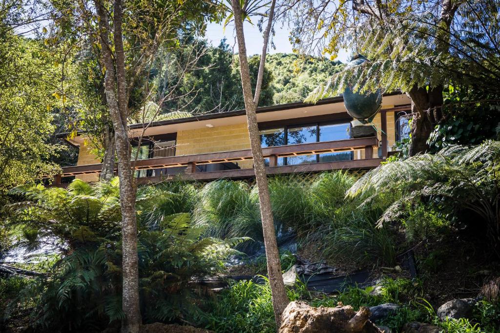 a house in the woods with a bridge at Maitai Whare Iti - Adventure Cabins & House in Nelson