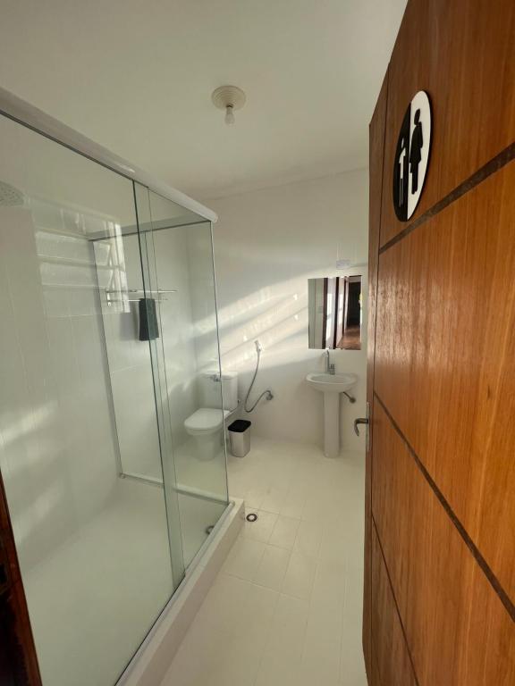 a bathroom with a glass shower and a toilet at Hostel Passa4 in Passa Quatro