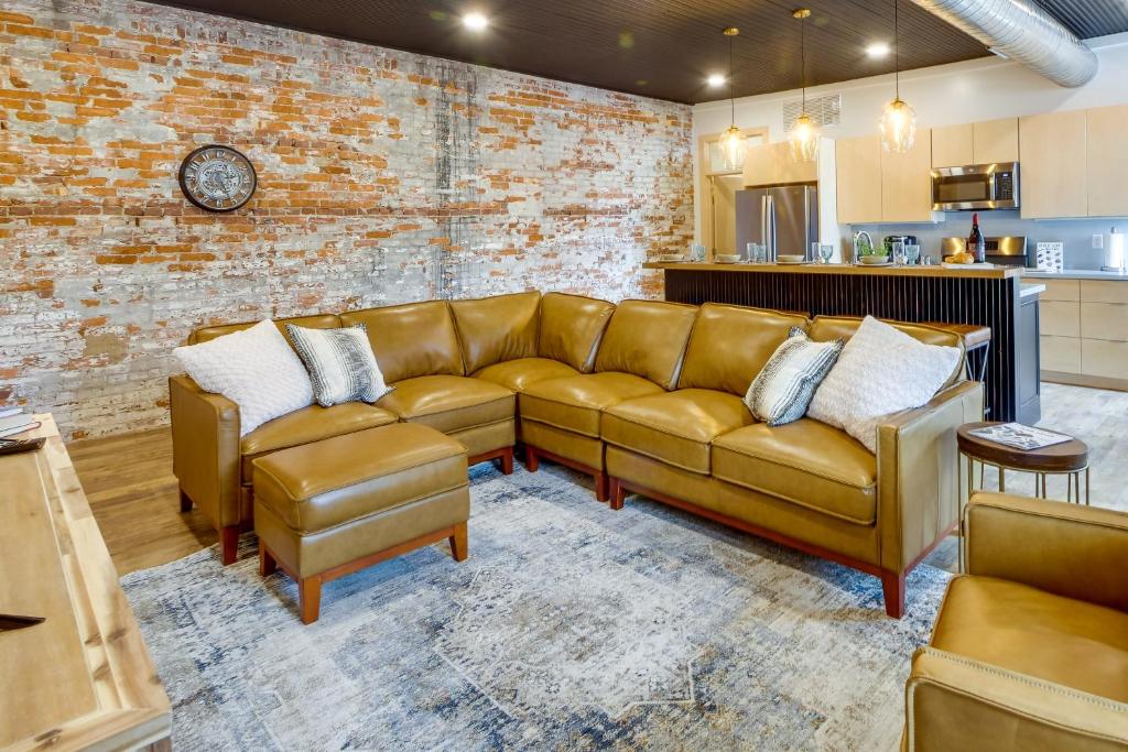 a living room with a couch and a brick wall at Downtown Millersburg Retreat with Sleek Interior! in Millersburg
