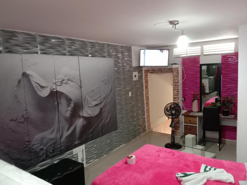 - une chambre avec un lit rose et un bureau dans l'établissement ALELI, NORTE cerca terminal, entr/sal aerpto, orquideorama,c de eventos valle del pcfco, base aérea mfs, à Cali