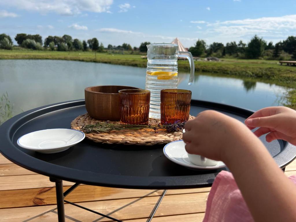 stół z dwoma kubkami i dzbanem wody w obiekcie Glamping Rusne w mieście Ruś