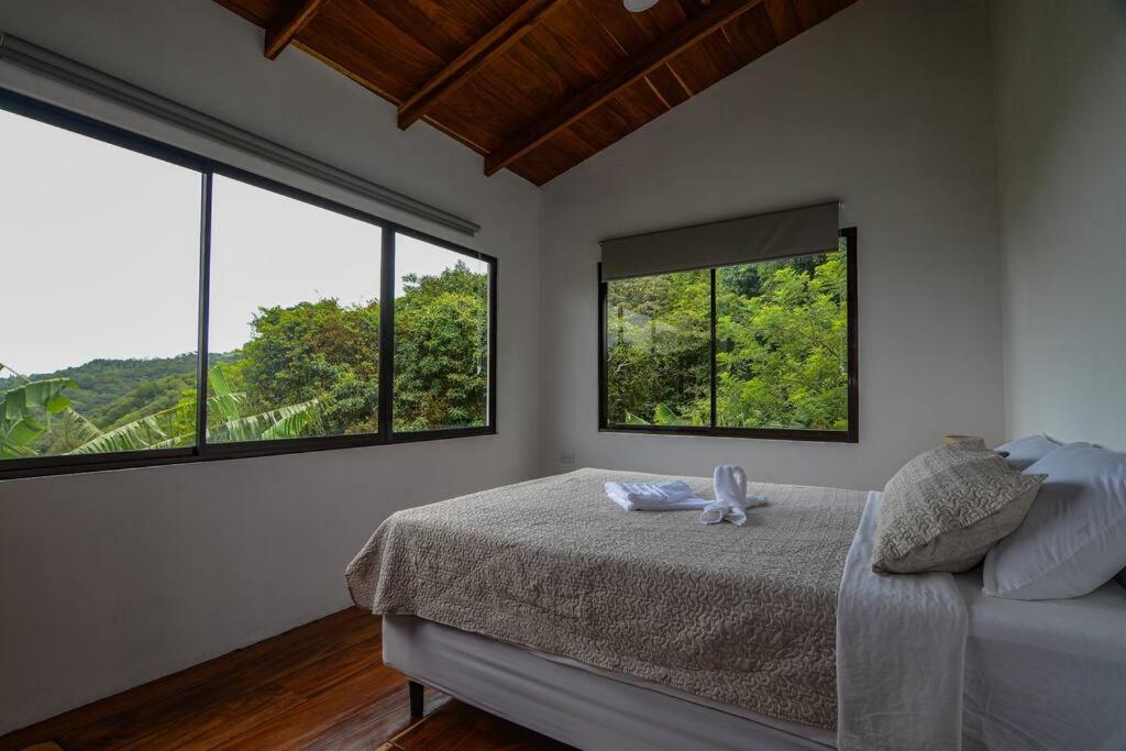 a bedroom with two large windows and a bed at Casa Curré Monteverde in Monteverde Costa Rica