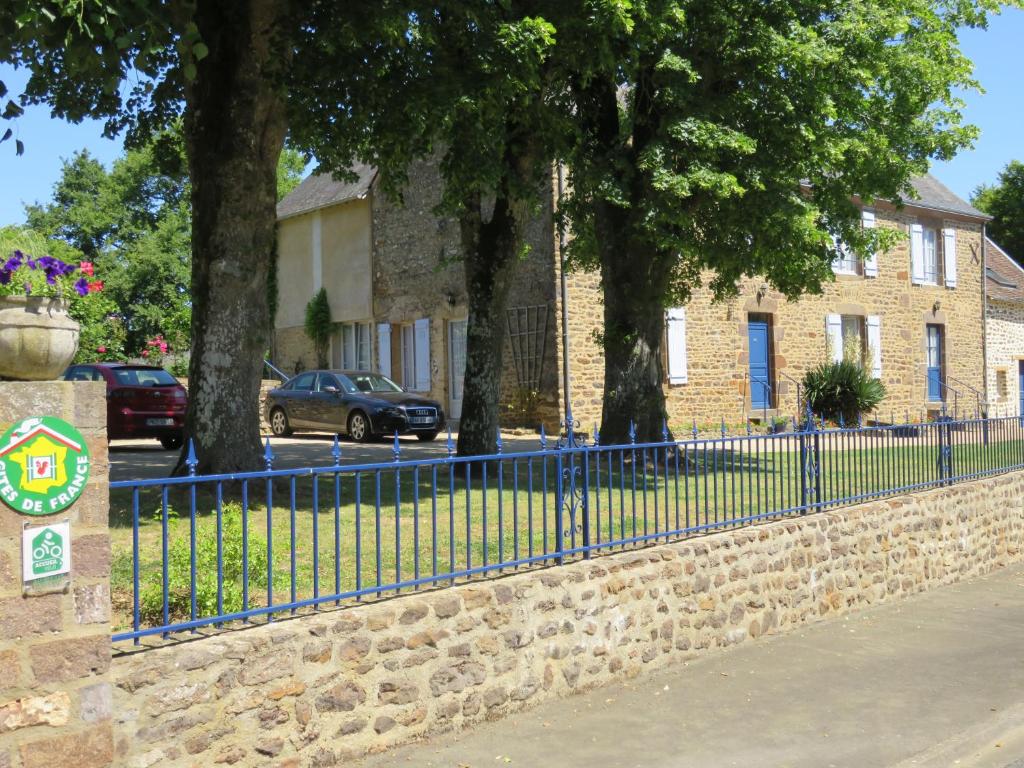 une clôture bleue devant un bâtiment arboré dans l'établissement Les Quatre Saisons, à Moitron-sur-Sarthe