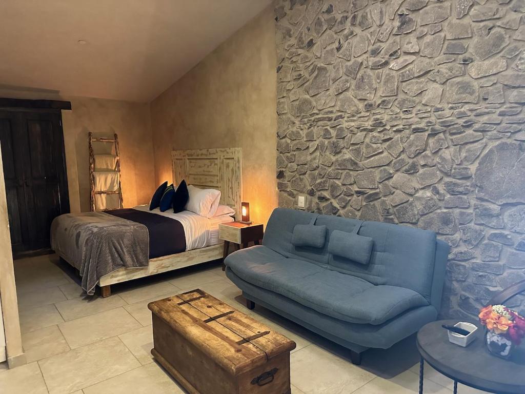 sypialnia z łóżkiem, kanapą i kamienną ścianą w obiekcie L’Appuntamento en Val'Quirico w mieście Santeagueda