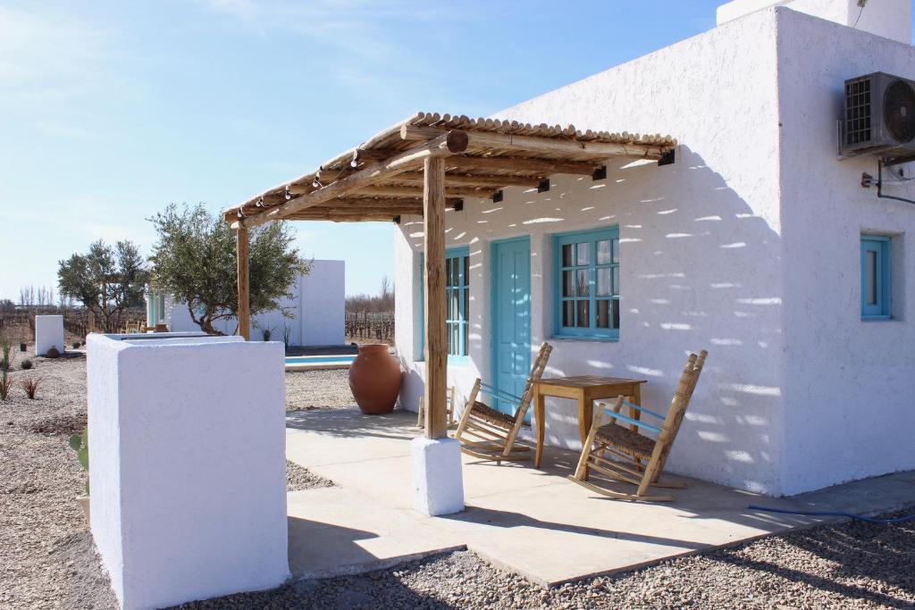 a small white house with a wooden pergola at Finca Rosablanca in Tunuyán