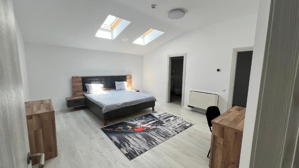 a white bedroom with a bed and a rug at Hotel Lavanda in Piteasca