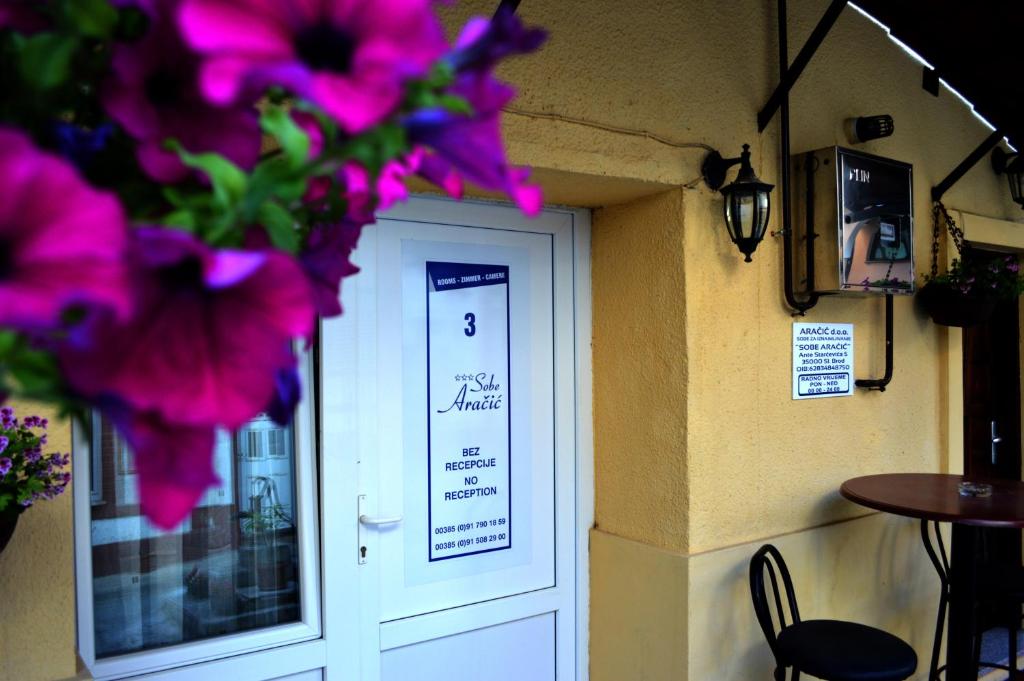 a white door with purple flowers in front of it at Rooms Aračić in Slavonski Brod