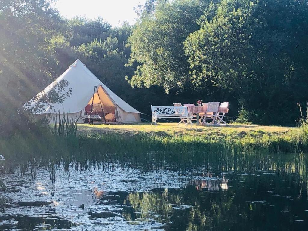 a tent with a table and a bench next to a lake at Rose glamping, self catering, bell tent in St Austell