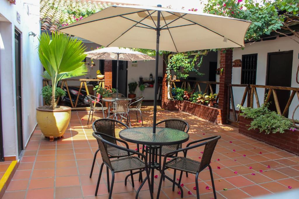 une terrasse avec une table, des chaises et un parasol dans l'établissement Hotel Colonial San Felipe, à Girón