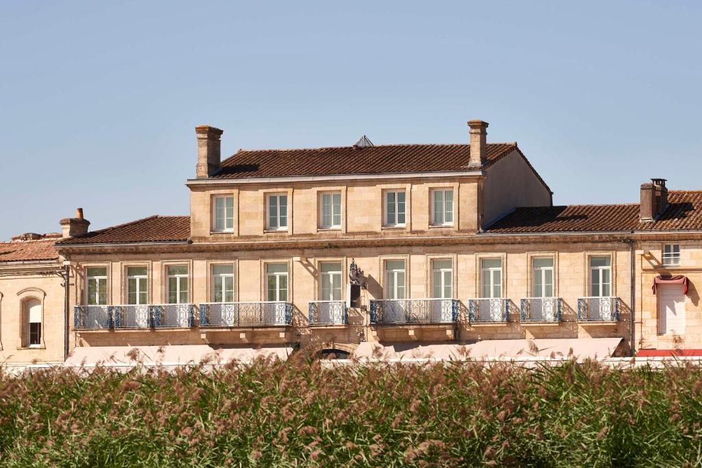a large building with a balcony in front of it at Best Western Premier Hotel des Vignes et des Anges in Pauillac