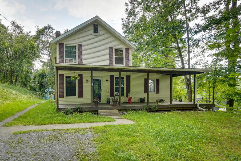 a small yellow house with a porch and a driveway at Lakefront West Sand Lake Home with Beach Access! in West Sand Lake