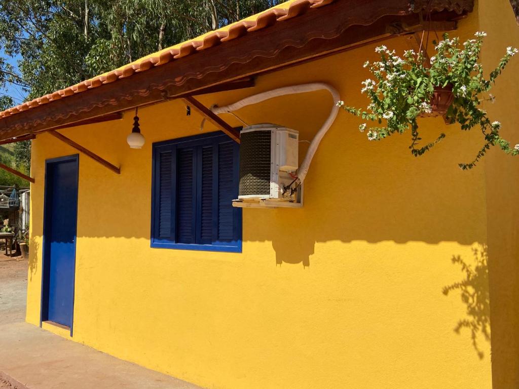 a yellow house with a blue window and a fan at Cantinho caipira in Aparecida