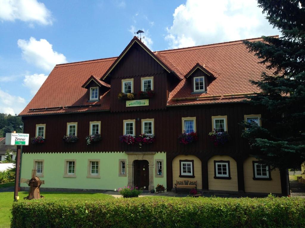 um grande edifício com caixas de flores na parte da frente em Pension Immergrün em Kurort Jonsdorf