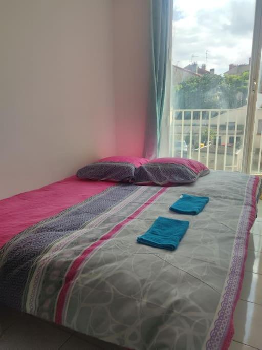 a bed with two blue towels on it with a window at Séjour chaleureux in Aubervilliers
