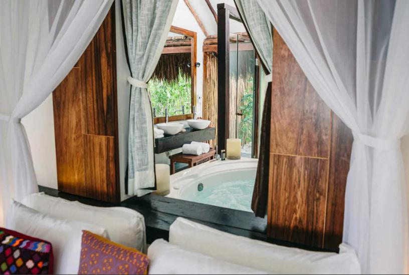 ein Badezimmer mit einer Badewanne, einem Fenster und einem Sofa in der Unterkunft Beachfront suites in Tulum beach in Tulum