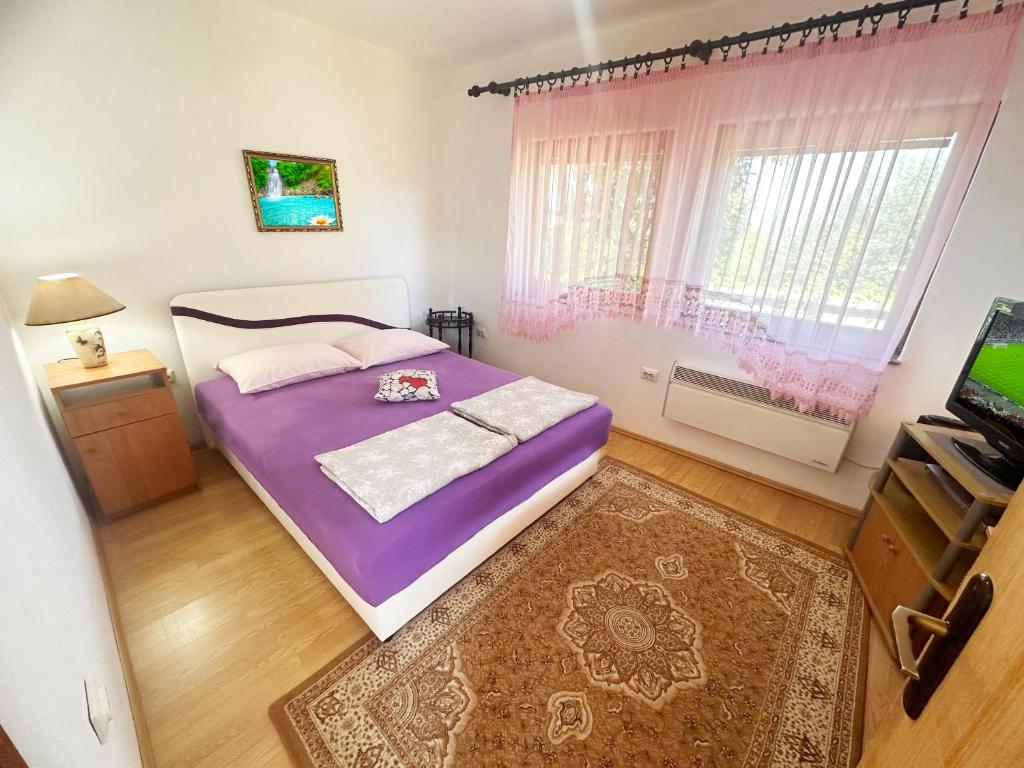 a bedroom with a purple bed and a television at Eko Apartment Sarajevo in Sarajevo