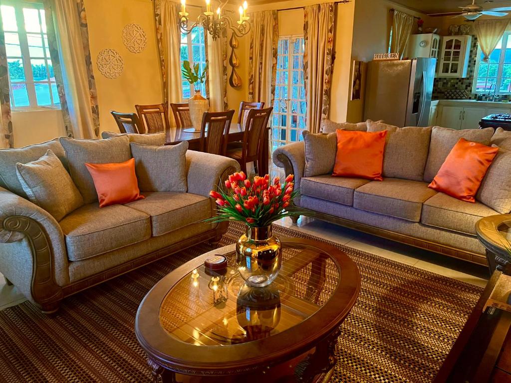 a living room with couches and a table with flowers on it at Pearls Place in Arima