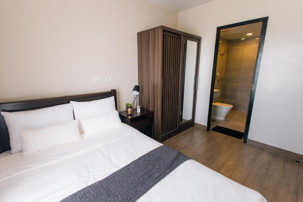 een slaapkamer met een groot wit bed en een badkamer bij The Onyx at One Regis Upper Penthouse flat in Bacolod