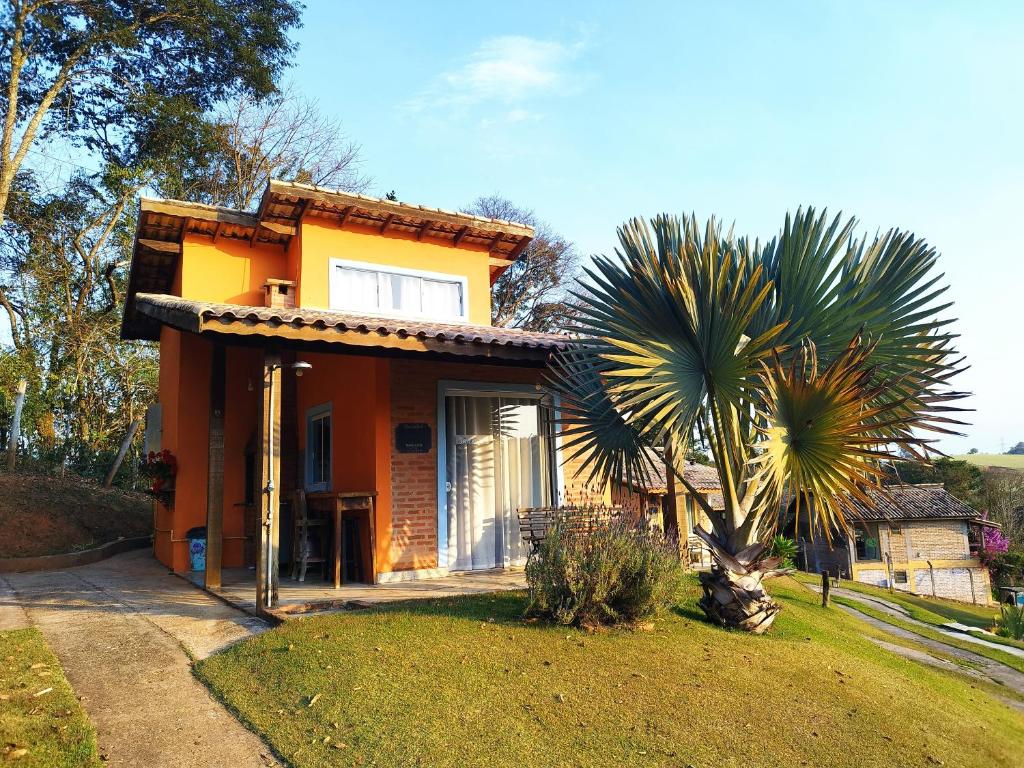 une petite maison avec un palmier en face dans l'établissement Chalé vista incrível Monte Alegre Village, à Monte Alegre do Sul