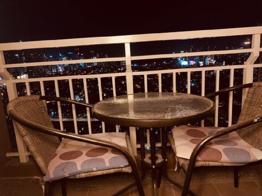 - une table et des chaises sur un balcon la nuit dans l'établissement Spacious 2BR near Uptown BGC, à Manille