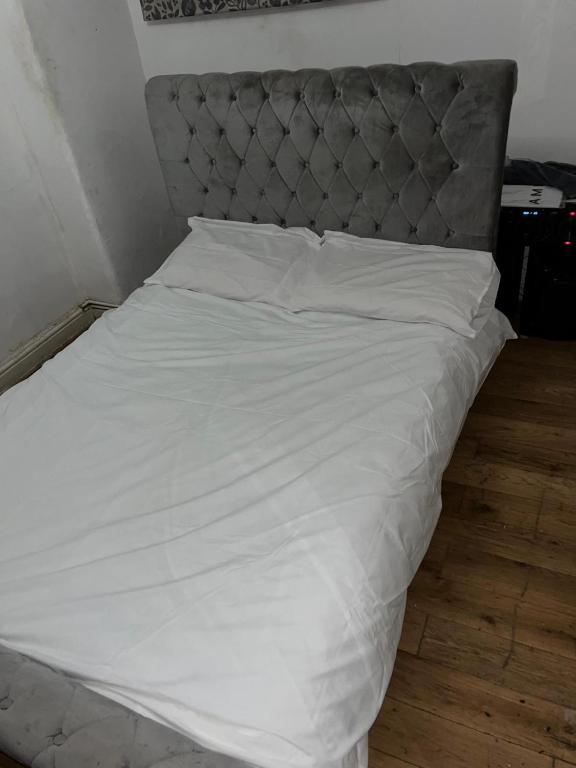 a white bed with a gray headboard and white sheets at Home 2 Home in London