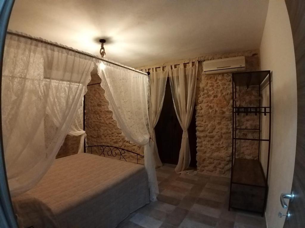 um quarto com uma cama e cortinas num quarto em A cantunera o castieddu em Naro