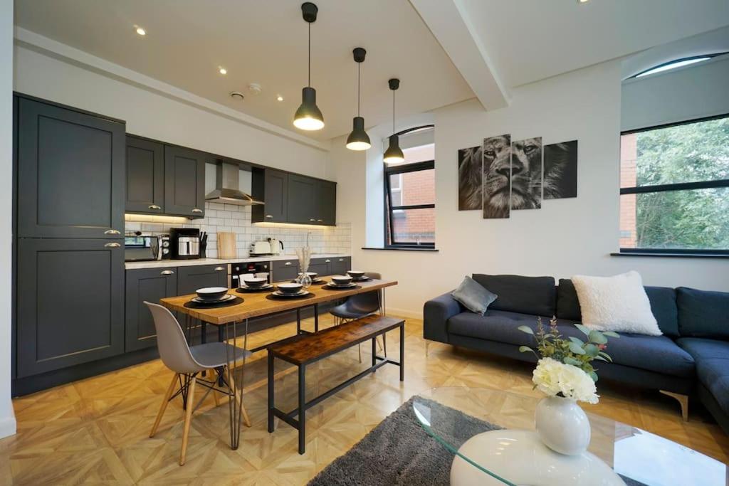 a kitchen and a living room with a couch and a table at Stylish & Elegant city centre apartment in Leeds