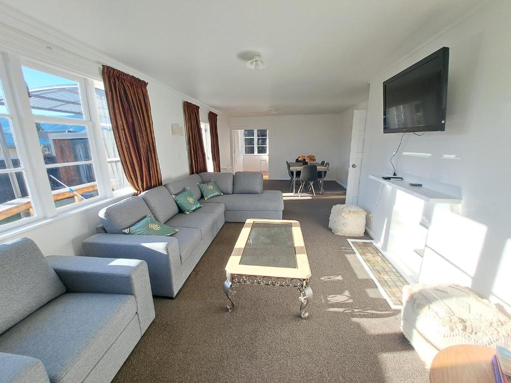 uma sala de estar com sofás azuis e uma televisão em 3bdrm plus Sleepot Home, em Nelson