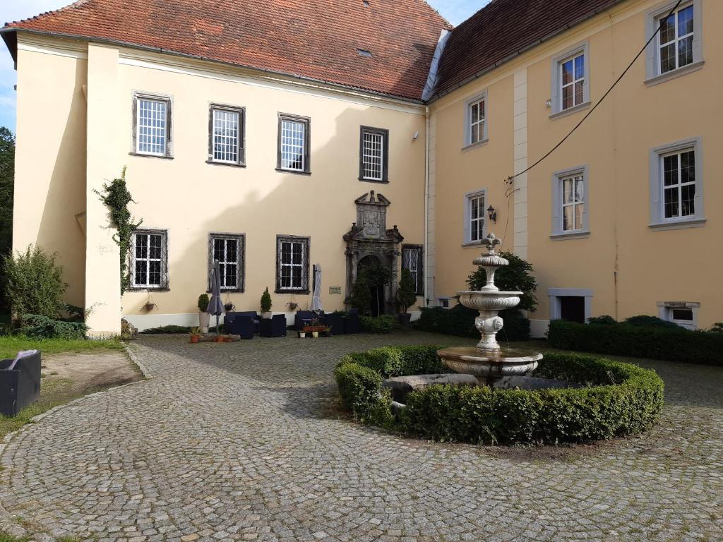 a courtyard with a fountain in front of a building at Pałac Lasów in Pieńsk