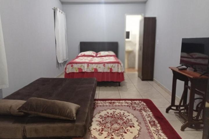 een woonkamer met een bank en een bed bij Kit net flor de café in Caparaó Velho