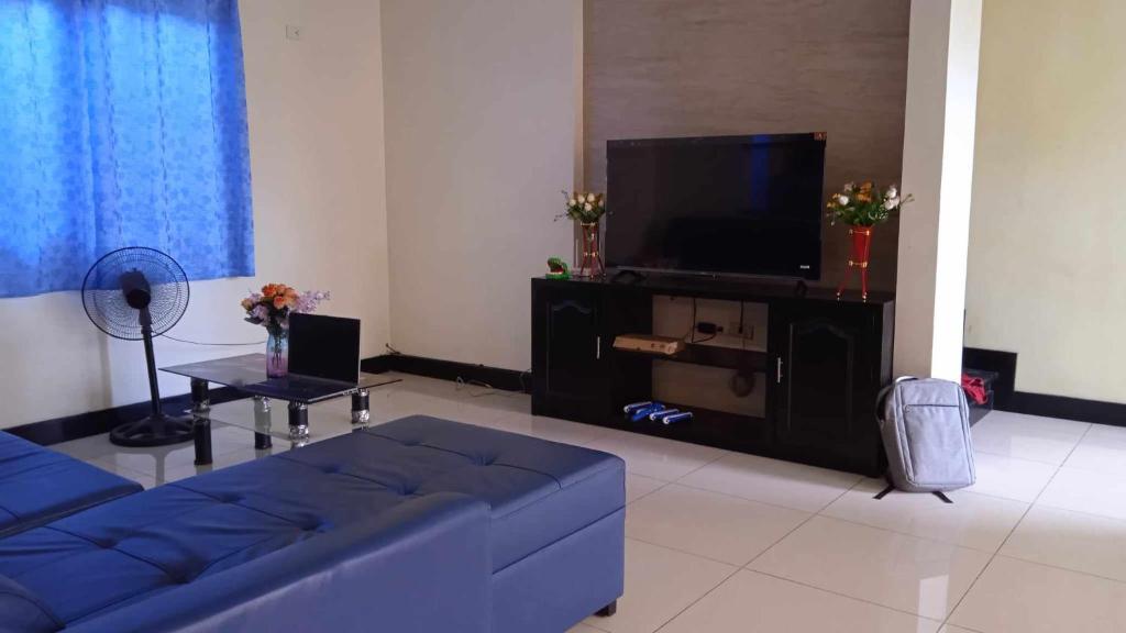 uma sala de estar com um sofá azul e uma televisão em Korean Town Pool Villa 2 em Angeles