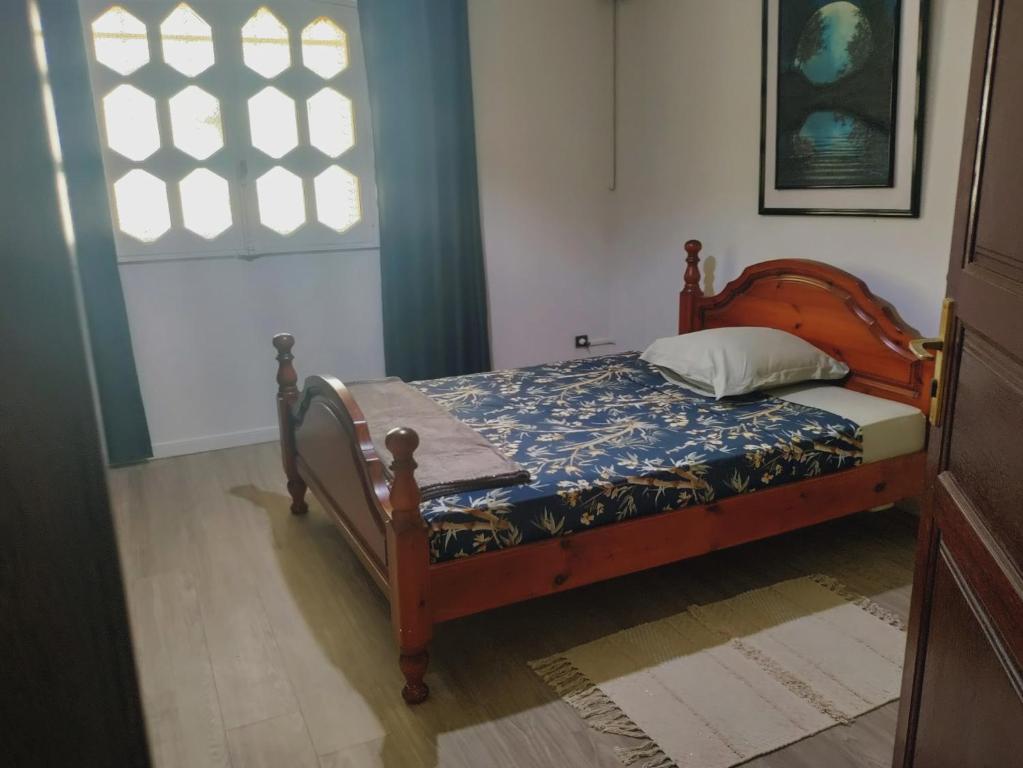 a bedroom with a bed with a wooden frame and a window at Villa Gardenia in Kourou