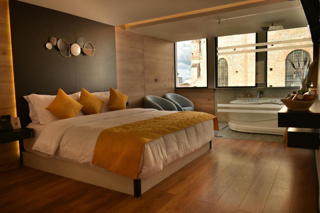 a bedroom with a large bed and a tub and windows at Hotel Vaway in Cuenca