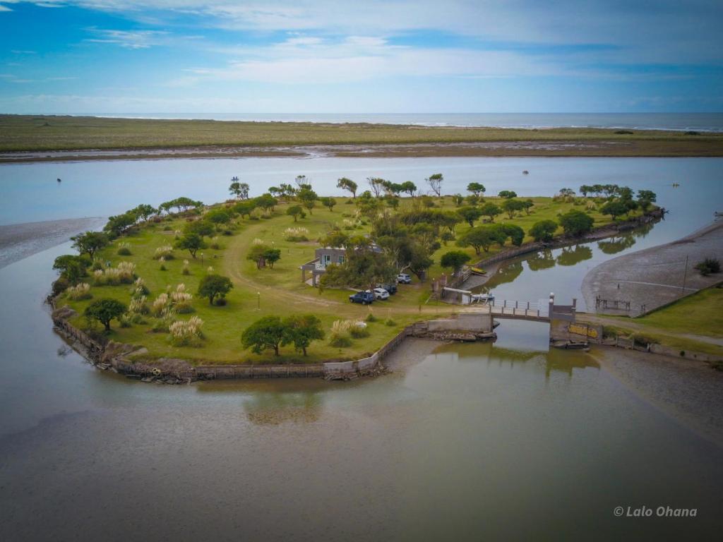 eine Insel inmitten eines Flusses mit einer Brücke in der Unterkunft COMPLEJO LA ISLA MAR CHIQUITA in Balneario Mar Chiquita