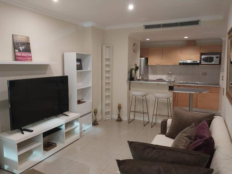 een woonkamer met een bank en een tv en een keuken bij Suite 211 in Quito