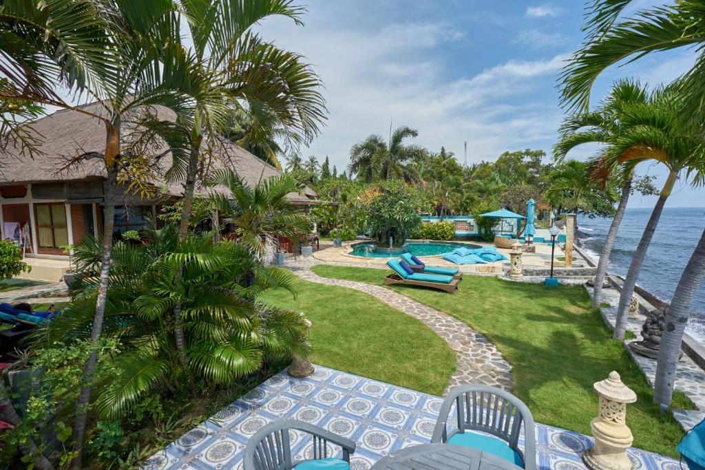 a resort yard with a swimming pool and palm trees at GRIYA BALI SURGA Waterfront Boutique Villa & Spa in Kubutambahan
