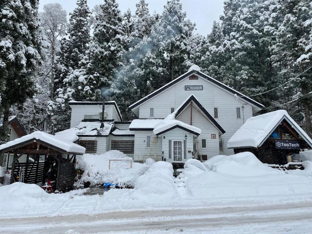 a house covered in snow next to a road at TaoTechHOUSE in Hakuba