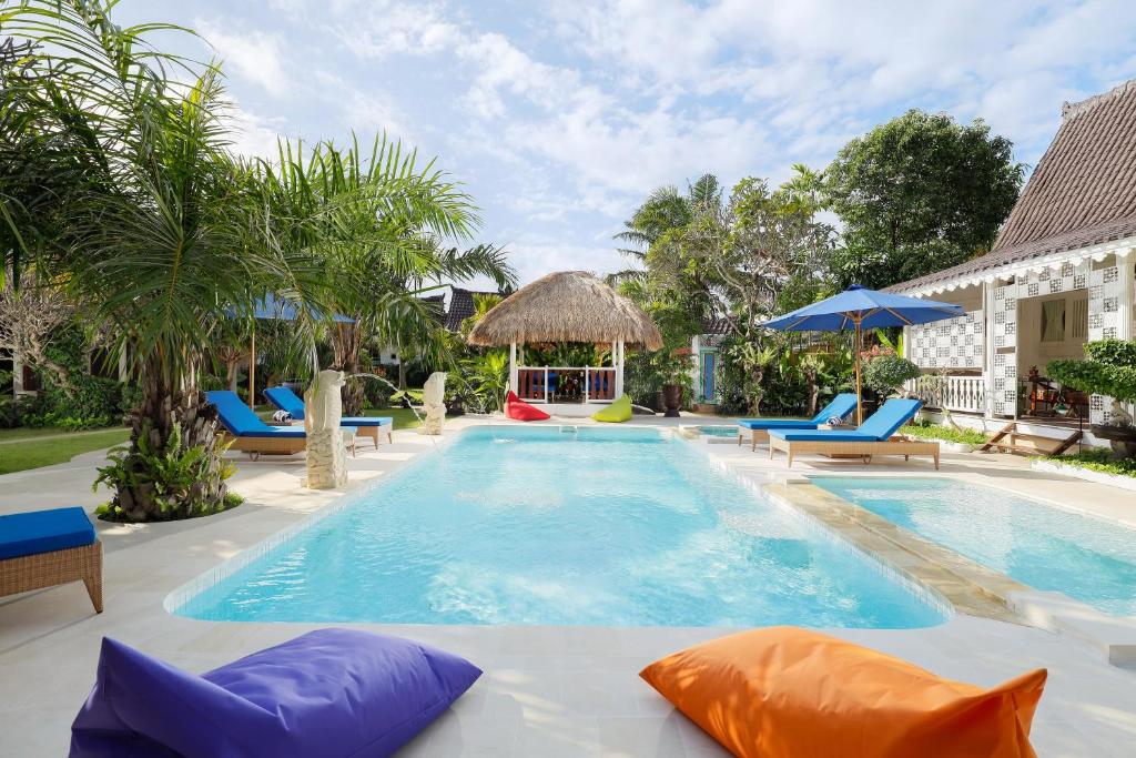 a pool with chairs and umbrellas at a resort at Puri Tempo Doeloe Boutique Hotel in Sanur