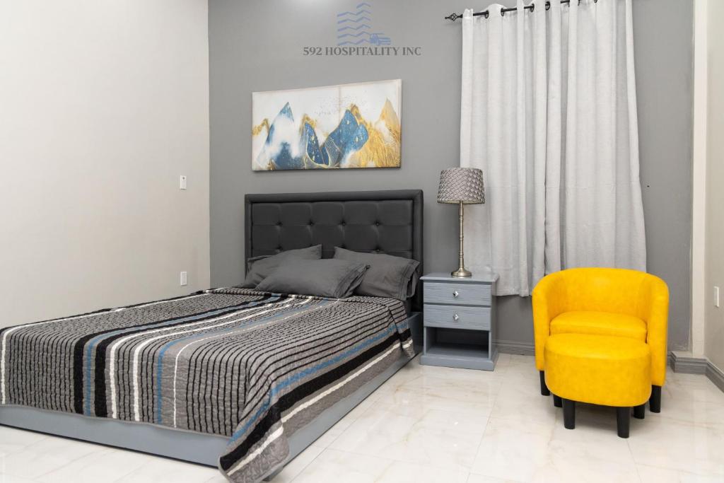 um quarto com uma cama e uma cadeira amarela em 592 Apartments 12 Duncan Street Campbellville, Georgetown em Georgetown