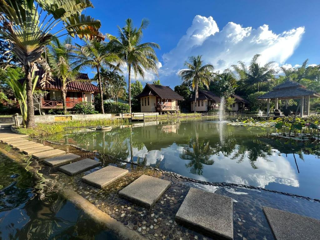 a pond in front of a resort with palm trees at Pairadise Hotel in Pai