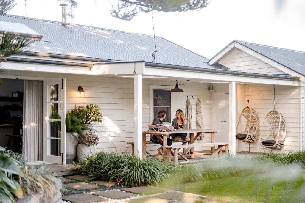 two people sitting at a table on the porch of a house at Soul of Gerringong Cottage in Gerringong