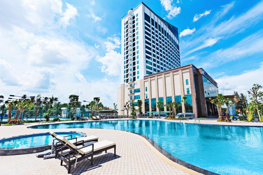 芹苴的住宿－芹苴孟清奢華酒店，酒店游泳池的背景是一座高高的建筑