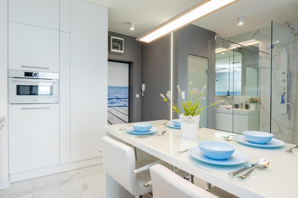 a white kitchen with a table with blue dishes on it at Wagonowa Premium Studio Chopin Airport in Warsaw