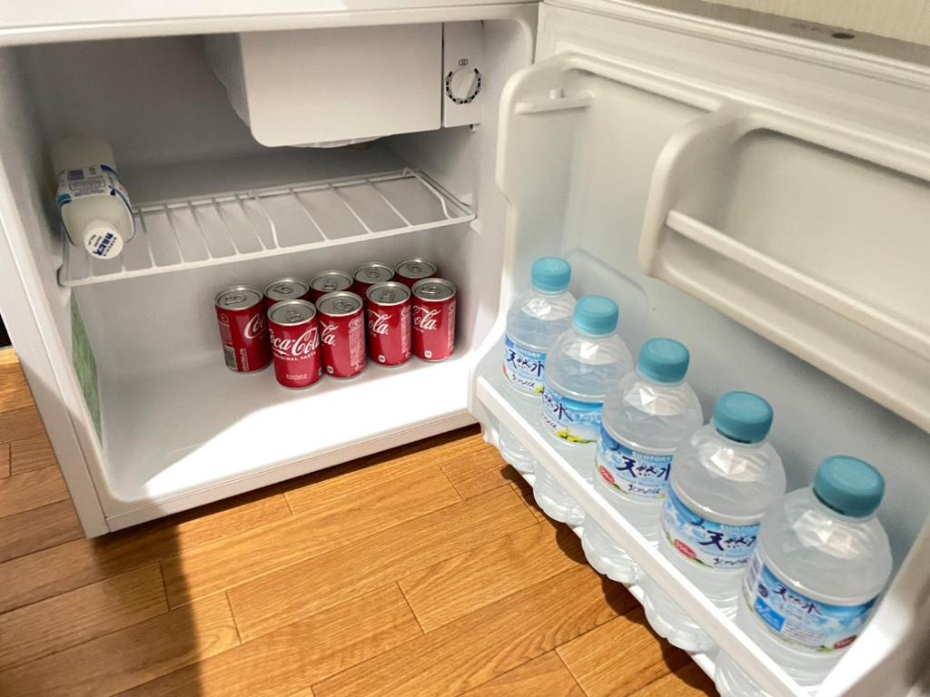 einem offenen Kühlschrank mit Wasserflaschen und Soda in der Unterkunft 民泊くるり in Nagoya