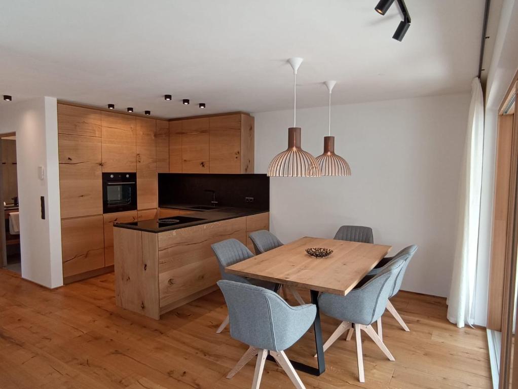 a kitchen and dining room with a wooden table and chairs at Dreamy Apartment by Lake Haider and Lake Reschen Uniting Luxury, Nature and Relaxation in San Valentino alla Muta