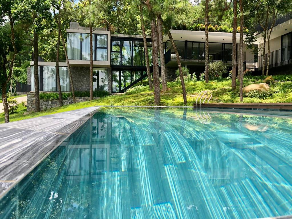 a swimming pool with blue water in front of a building at Tam Dao Retreat Venuestay in Tam Ðảo