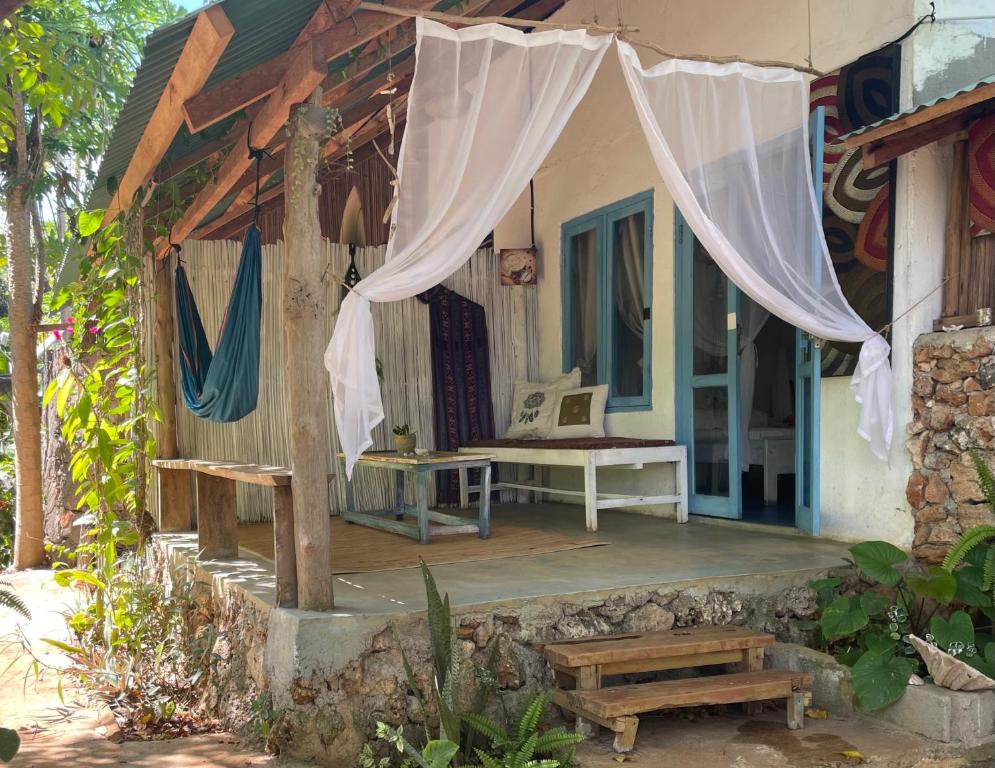 um alpendre de uma casa com uma cama e cortinas em Blu oceano B&B, Italian restaurant em Nembrala