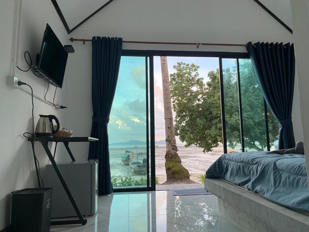 a bedroom with a large window with a view of the ocean at Mook tawan Beach house in Koh Mook