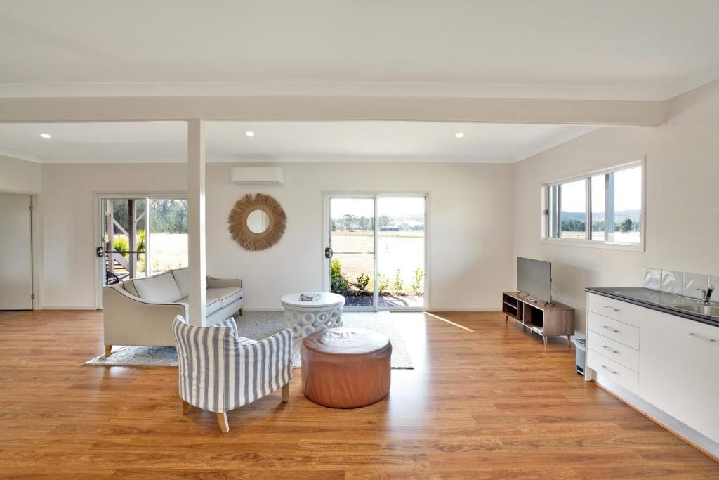 a living room with wooden floors and white walls at Emma's Cottage Vineyard in Lovedale